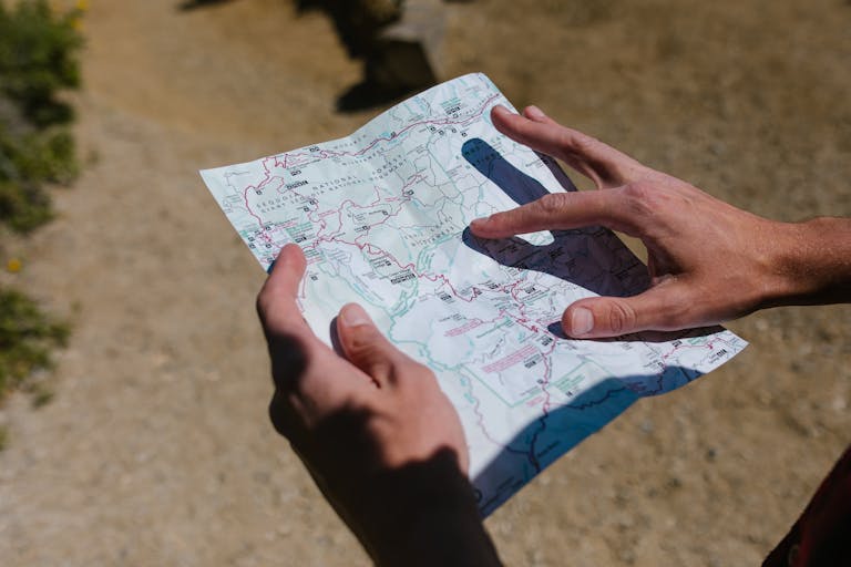 Close-up of hands holding a map during an outdoor adventure on a sunny day.